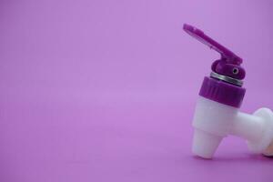 closed faucet isolated purple background. the faucet is white with a purple lid photo