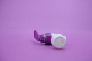 closed faucet isolated purple background. the faucet is white with a purple lid photo