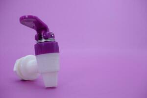 closed faucet isolated purple background. the faucet is white with a purple lid photo