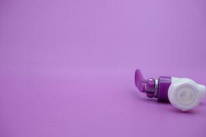closed faucet isolated purple background. the faucet is white with a purple lid photo