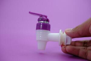 hand holding faucet isolated purple background. photo