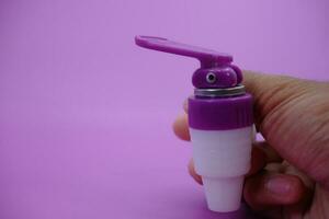 hand holding faucet isolated purple background. photo