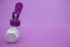 open faucet isolated purple background. white faucet with purple lid. photo