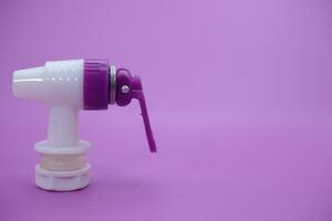 closed faucet isolated purple background. the faucet is white with a purple lid photo