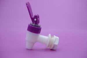 open faucet isolated purple background. white faucet with purple lid. photo