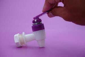 hand holding faucet isolated purple background. photo