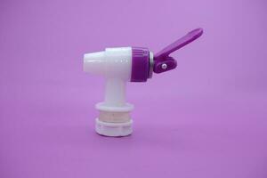 open faucet isolated purple background. white faucet with purple lid. photo