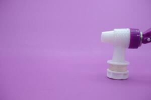 open faucet isolated purple background. white faucet with purple lid. photo