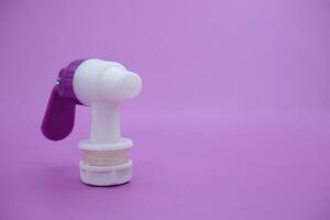 closed faucet isolated purple background. the faucet is white with a purple lid photo