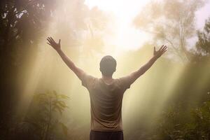 a man standing in the middle of the forest with arms outstretched in the bright morning sunray. photo