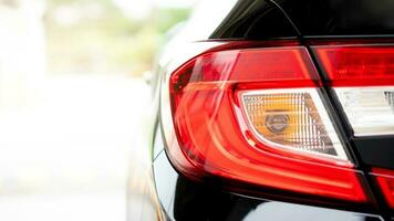 Close up tail light of black car. In the pakring lot. with abstract and blurred of background with sunlight. photo