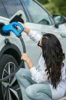 Young business woman refueling her electric car at a EV charging station. Concept of environmentally friendly vehicle. Electric car concept. Green travelling. photo