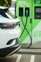 Young business woman refueling her electric car at a EV charging station. Concept of environmentally friendly vehicle. Electric car concept. Green travelling. photo