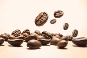 Falling coffee beans and freshly roasted coffee beans on beige background. photo