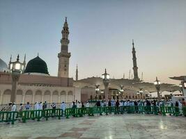 Medina, Saudi Arabia, May 2023 - Beautiful morning view of Masjid Al Nabawi, Medina. Visitors, courtyards outside the mosque, beautiful lights,  and electronic umbrellas can also be seen. photo