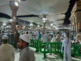 Medina, Saudi Arabia, May 2023 - Beautiful night time view of Masjid Al Nabawi, Medina. Visitors, courtyards outside the mosque, beautiful lights and electronic umbrellas can also be seen. photo