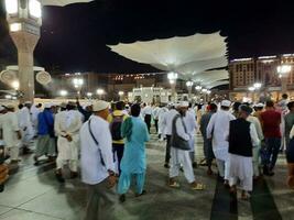 Medina, Saudi Arabia, May 2023 - Beautiful night time view of Masjid Al Nabawi, Medina. Visitors, courtyards outside the mosque, beautiful lights and electronic umbrellas can also be seen. photo