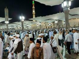 Medina, Saudi Arabia, May 2023 - Beautiful night time view of Masjid Al Nabawi, Medina. Visitors, courtyards outside the mosque, beautiful lights and electronic umbrellas can also be seen. photo