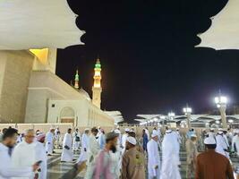 Medina, Saudi Arabia, May 2023 - Beautiful night time view of Masjid Al Nabawi, Medina. Visitors, courtyards outside the mosque, beautiful lights and electronic umbrellas can also be seen. photo