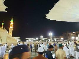 Medina, Saudi Arabia, May 2023 - Beautiful night time view of Masjid Al Nabawi, Medina. Visitors, courtyards outside the mosque, beautiful lights and electronic umbrellas can also be seen. photo