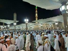 Medina, Saudi Arabia, May 2023 - Beautiful night time view of Masjid Al Nabawi, Medina. Visitors, courtyards outside the mosque, beautiful lights and electronic umbrellas can also be seen. photo