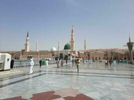 Medina, Saudi Arabia, May 2023 - A beautiful daytime view of Masjid Al Nabawi, Medina's outer courtyard, pilgrims and mosque canopies. photo