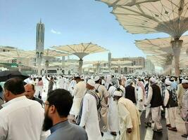 Medina, Saudi Arabia, May 2023 - A beautiful daytime view of Masjid Al Nabawi, Medina's outer courtyard, pilgrims and mosque canopies. photo