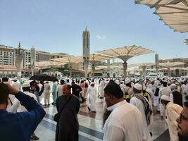 Medina, Saudi Arabia, May 2023 - A beautiful daytime view of Masjid Al Nabawi, Medina's outer courtyard, pilgrims and mosque canopies. photo