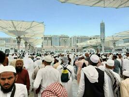 Medina, Saudi Arabia, May 2023 - A beautiful daytime view of Masjid Al Nabawi, Medina's outer courtyard, pilgrims and mosque canopies. photo