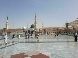 Medina, Saudi Arabia, May 2023 - A beautiful daytime view of Masjid Al Nabawi, Medina's outer courtyard, pilgrims and mosque canopies. photo