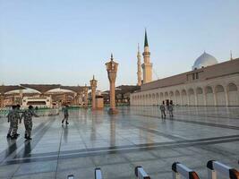 Medina, Saudi Arabia, May 2023 - A beautiful daytime view of Masjid Al Nabawi, Medina's outer courtyard, pilgrims and mosque canopies. photo