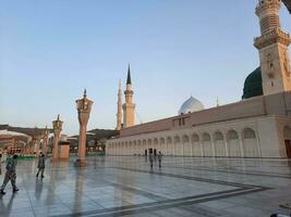 Medina, Saudi Arabia, May 2023 - A beautiful daytime view of Masjid Al Nabawi, Medina's outer courtyard, pilgrims and mosque canopies. photo