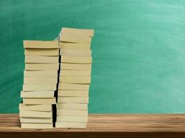 stack of books on wooden table There is a green board background. photo