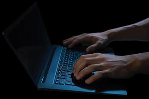 Man working on laptop computer in the dark. photo