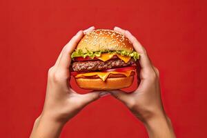 Hands holding a hamburger isolated on red background. photo