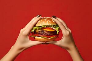 Hands holding a hamburger isolated on red background. photo