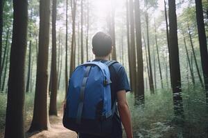Back view young man with a backpack standing the forest. Freedom and nature concept. photo