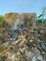 Garbage and useless items are burned on the edge of the rice fields photo