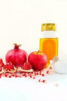 Whole pomegranate, pomegranate seeds, red apple and honey, on white background. Jewish New Year symbols. photo