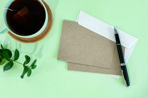 Creative flat lay photo of workspace desk with rustic sheet, envelope, pen and tea cup.