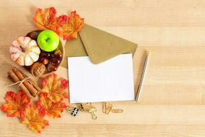 Autumn maple leaves over wooden background, greeting and pen. photo
