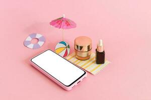 Assembling the skin care cream bottle container, beach umbrella and smart phone on pink background. Summer travel and vacation concept. Beauty and cosmetics concept. photo