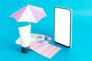 Assembling the skin care cream bottle container, beach umbrella and smart phone on light blue background. Summer travel and vacation concept. Beauty and cosmetics concept. photo
