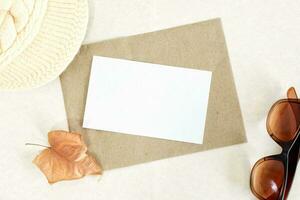 Invitation or greeting card mockup with dry leaf decorations on beige paper background. photo