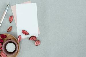 Blank pink and white card with candle and petals, on gray background. photo