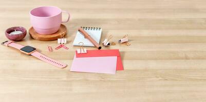 Office desk with tea cup, notebook, pen, card and envelope. Wooden desktop. photo