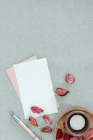 Blank pink and white card with candle and petals, on gray background. photo