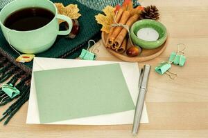 Autumn or winter season cozy composition with greeting card, tea cup, pen, on desk table. photo