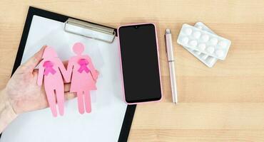 Hand holding women's figurines with pink ribbons. Breast cancer awareness and October Pink day. World cancer day. photo