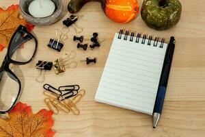 Notepad with a pen, supplies and autumn leaves. photo